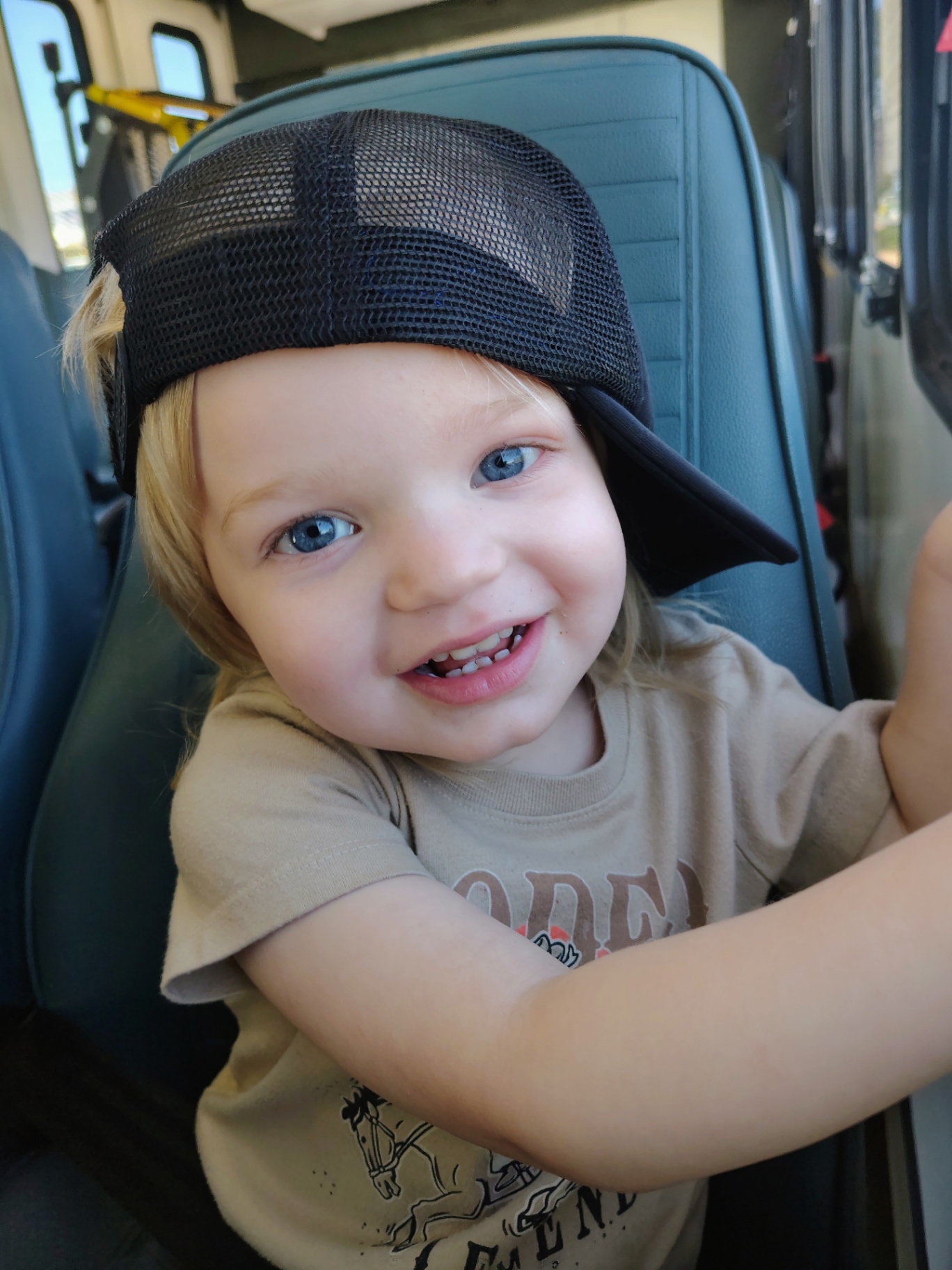 The little menace himself, all smiles in a trucker hat